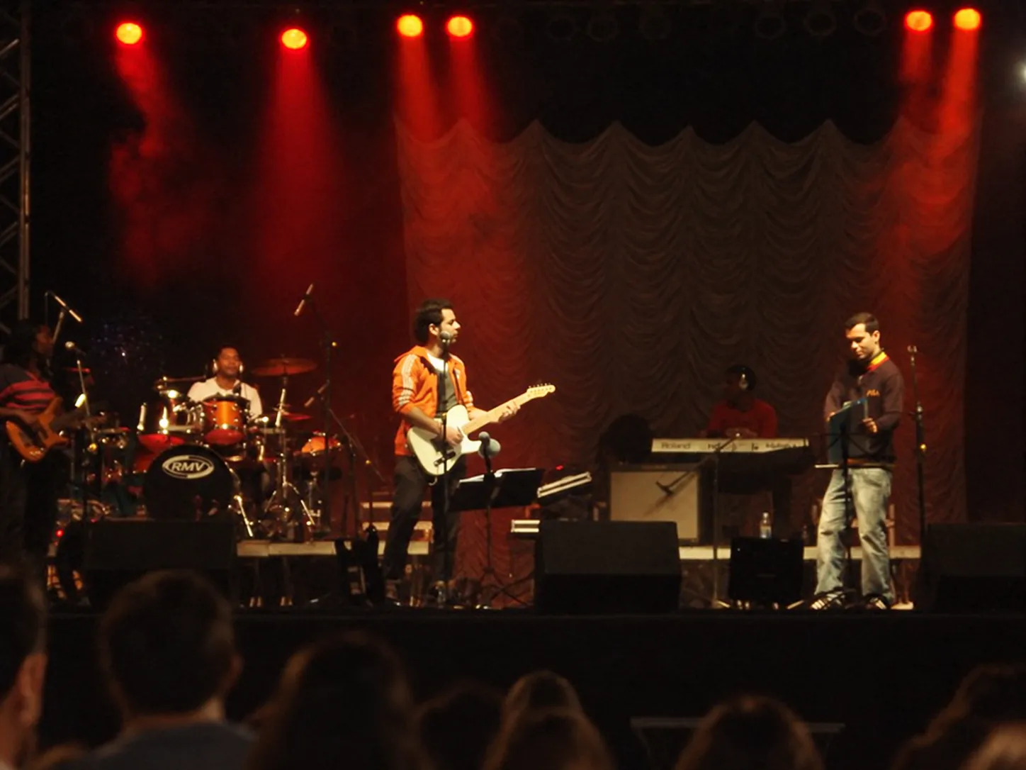 Pablo Curty e banda num palco grande com luzes vermelhas.
